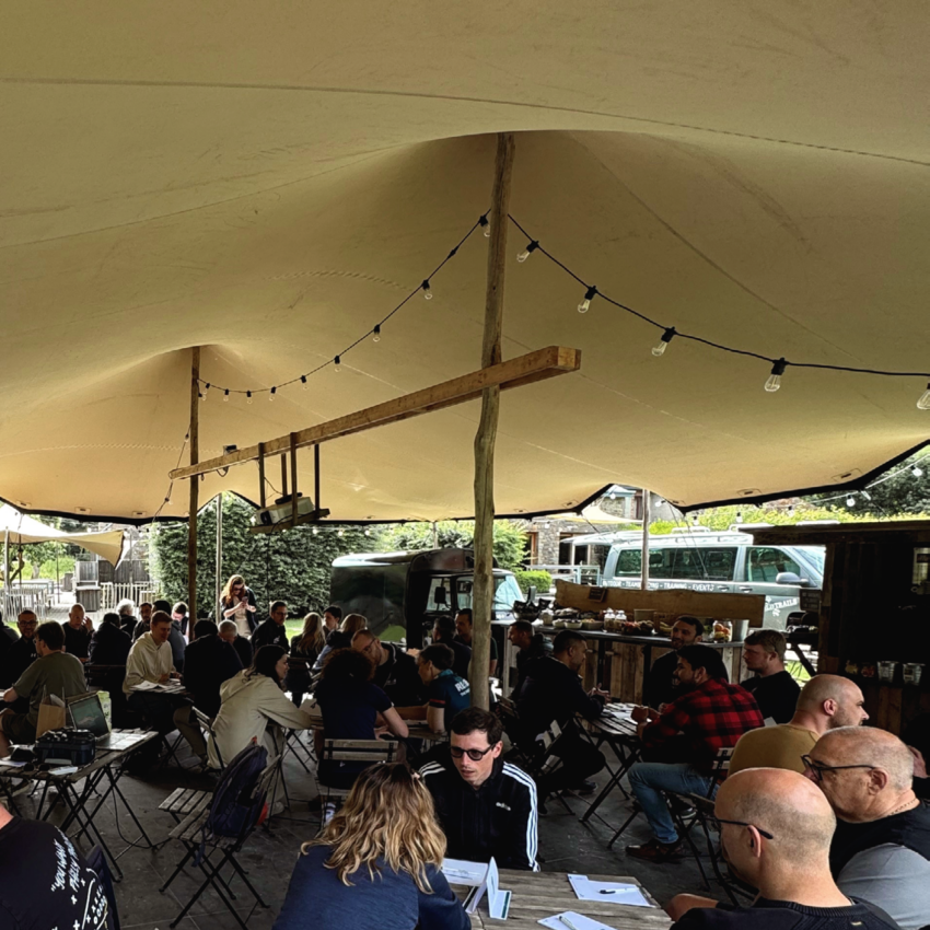 REAZN employees seated together under a tent during an outdoor team event